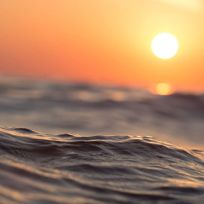 Bild på böljande vatten och en solnedgång